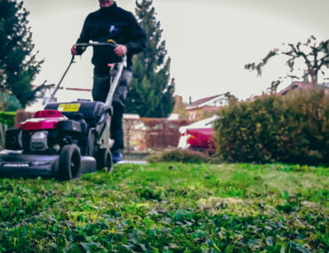 Mitarbeiter am Rasenmähen als Teil der regulären Gartenarbeit.