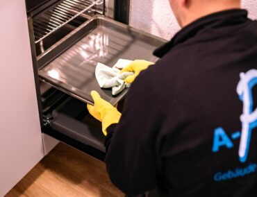 Mitarbeiter putzt Backofen als Teil der Endreinigung.